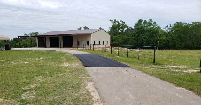 A road leading to a building in the middle of a field