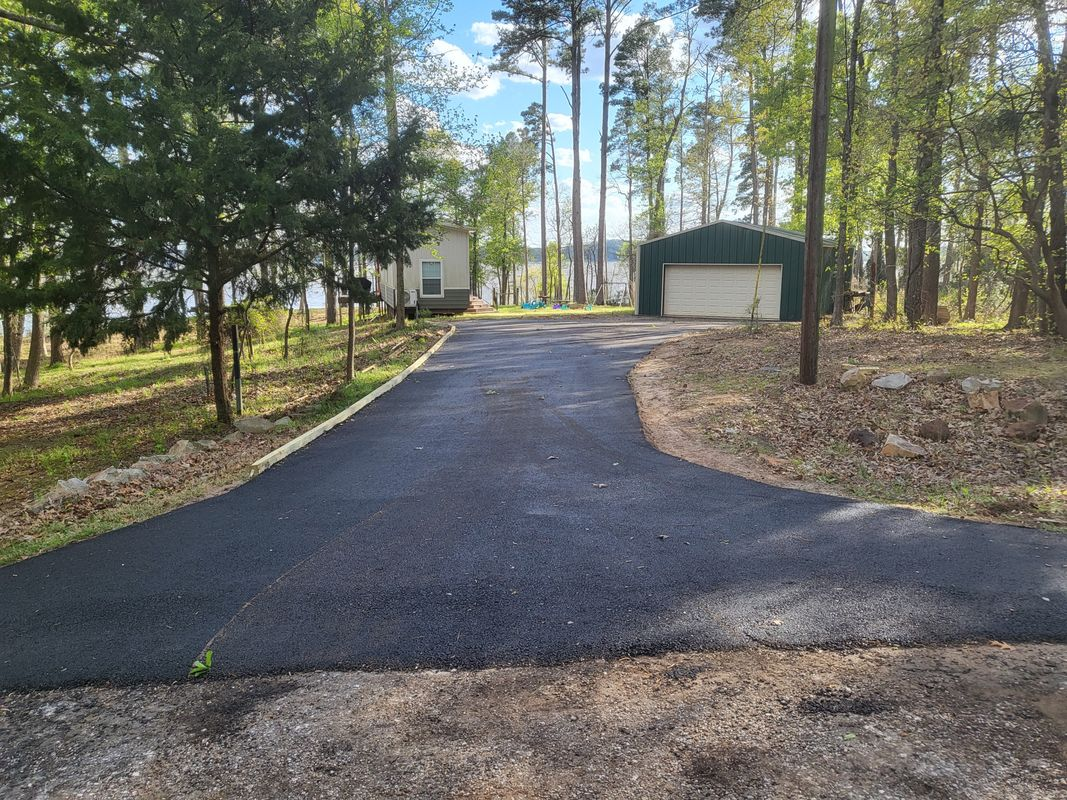 A driveway leading to a house surrounded by trees and a garage