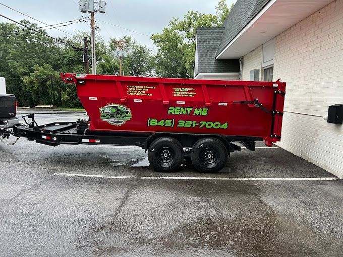 A red dumpster is parked in a parking lot next to a building.