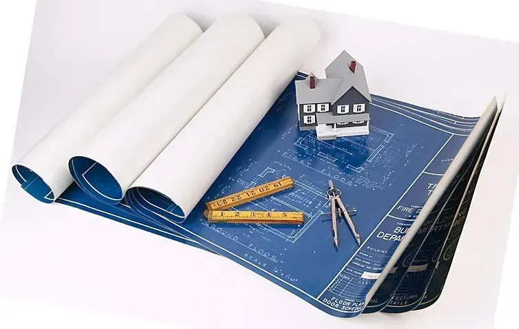 Blueprints, rolled and open, with small house model, ruler, and compass.