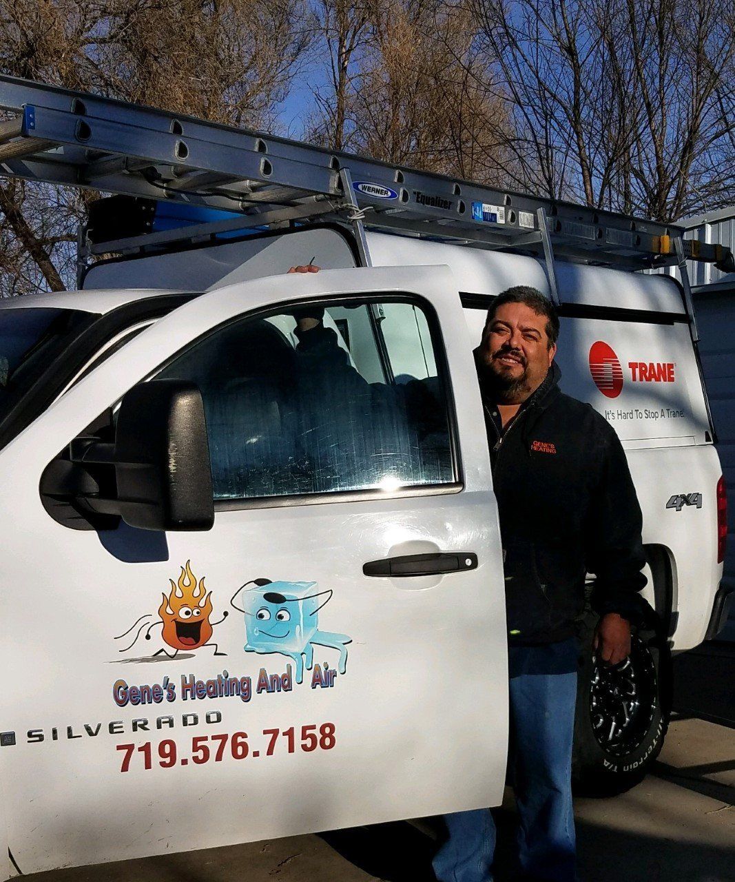 Man in black jacket stands by white truck; 