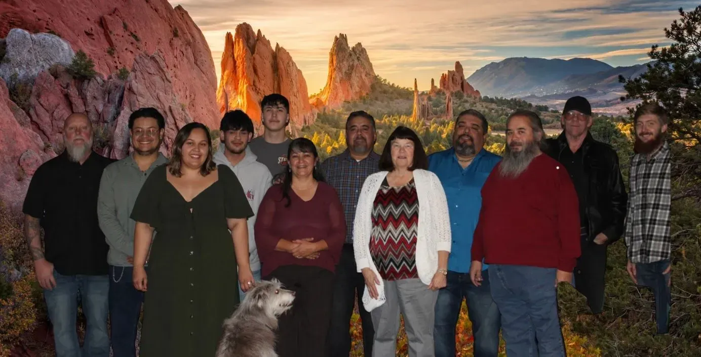 Group of people posing for a photo in front of a scenic mountain background.