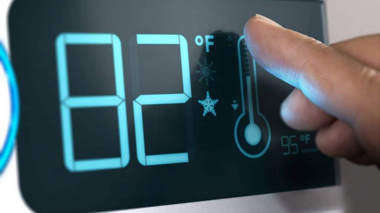 Hand adjusting thermostat set to 82°F.