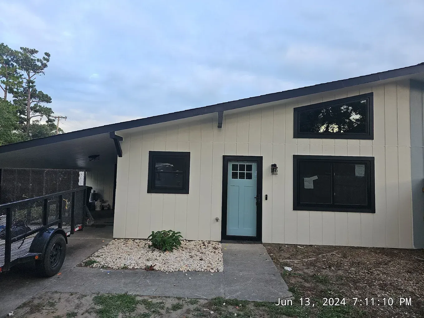 Narrow hallway with dark wood floors, white walls, and closed doors. A window is at the end of the hall.