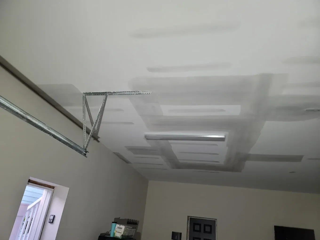Garage ceiling with drywall patches around a garage door opener and recessed lights.
