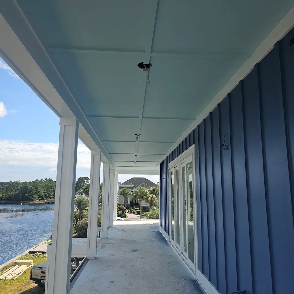 Blue and white veranda with water view; blue siding, ceiling, and trim, white columns.