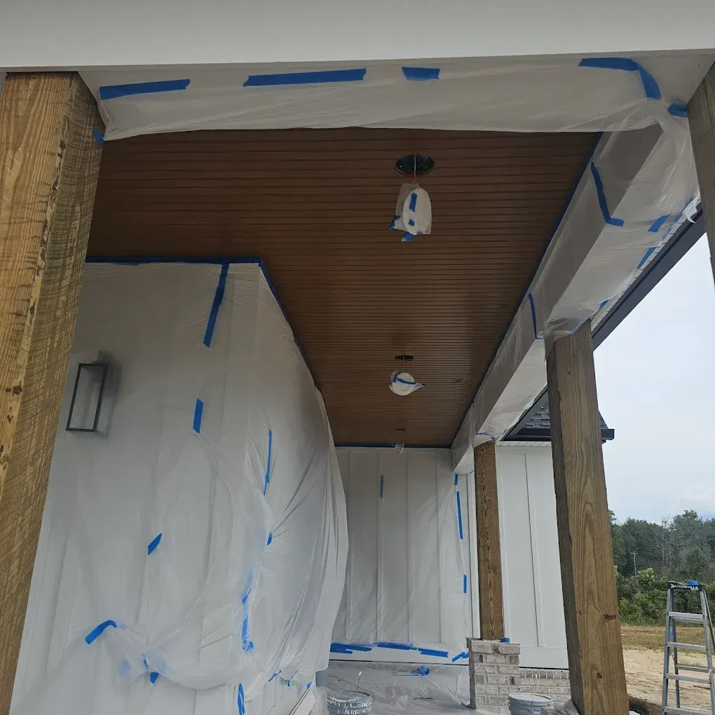 Porch ceiling painted brown, walls and support beams wrapped in plastic and taped.