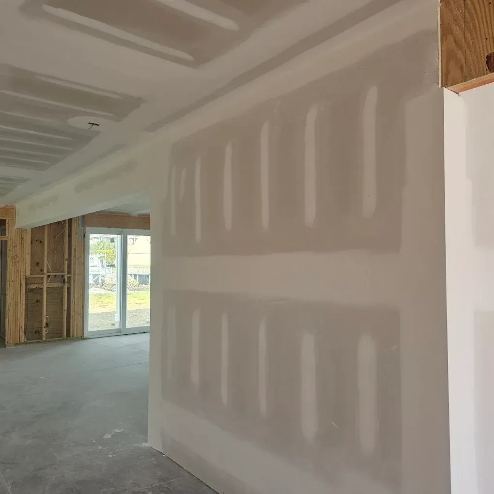 Interior wall and ceiling with drywall in progress, doorway, and unfinished wooden framing.