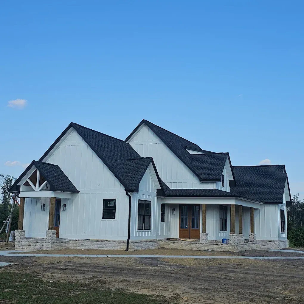 White farmhouse with black roof under a clear blue sky.