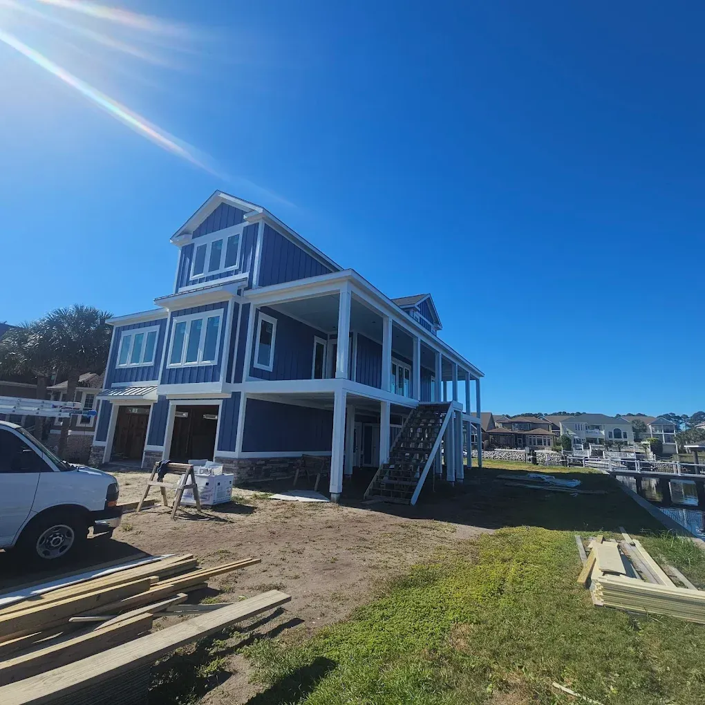 Blue house under construction with white trim, clear blue sky.