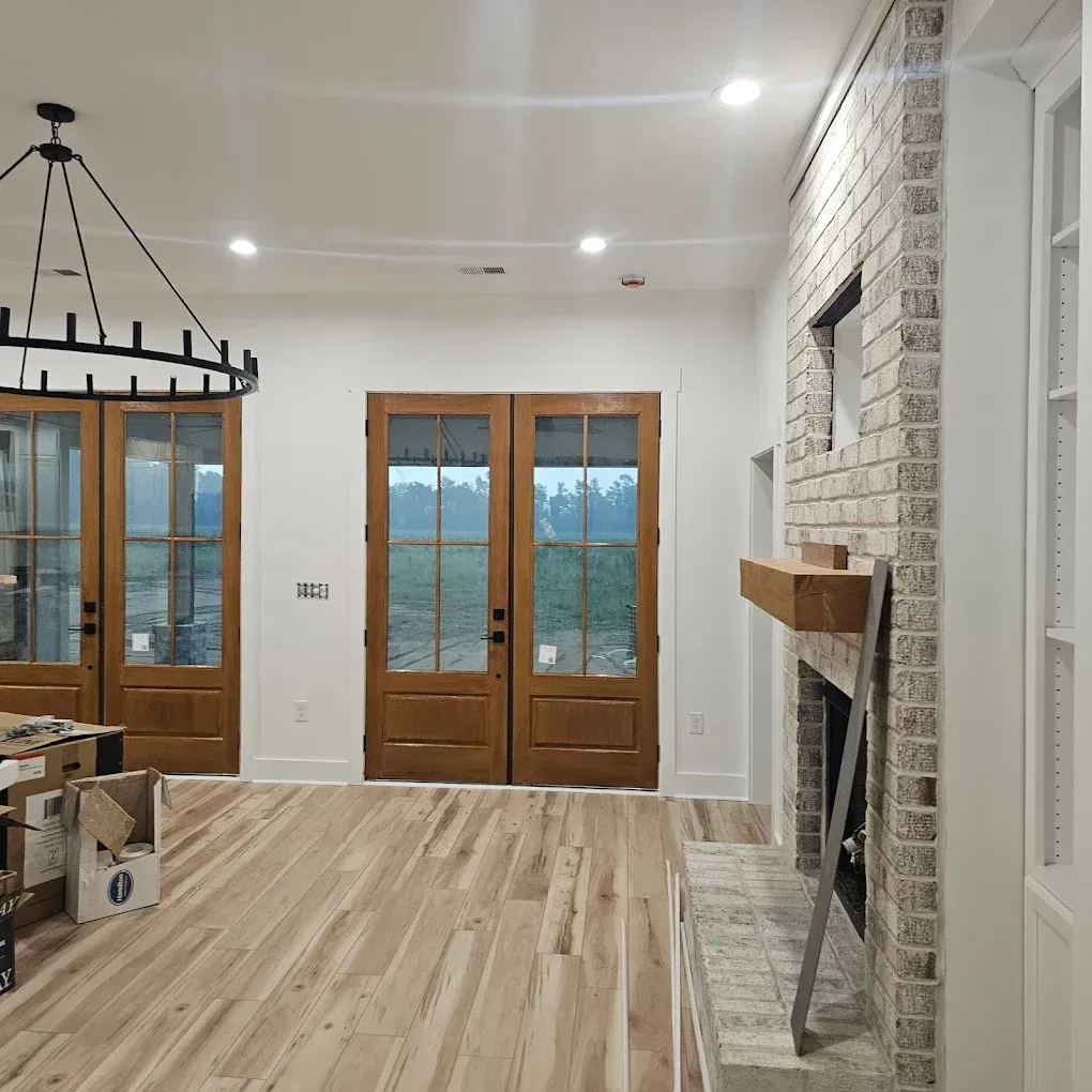 Interior with hardwood floors, wooden doors, and brick fireplace.