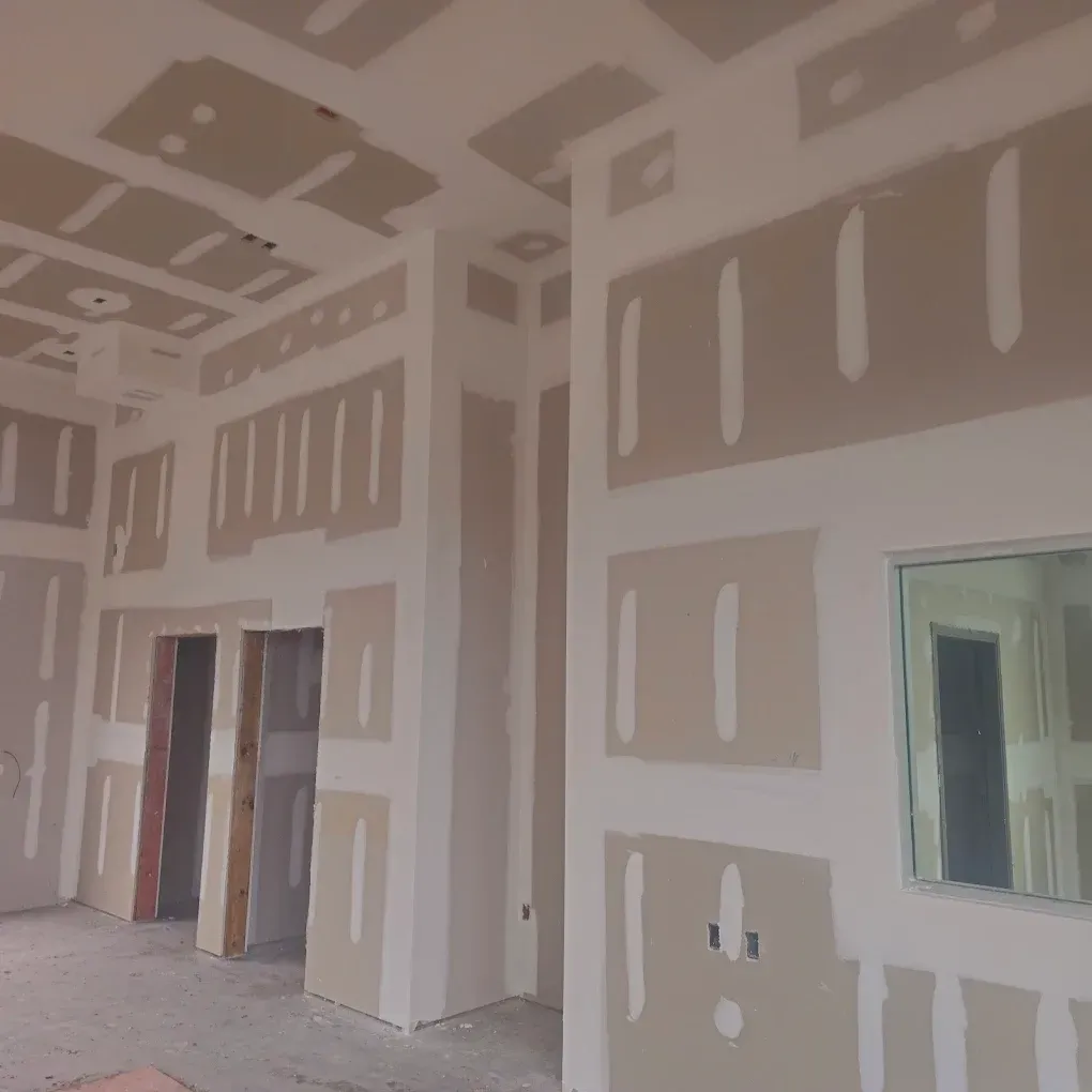 Interior of a building under construction, showing drywall installed on walls and ceiling.