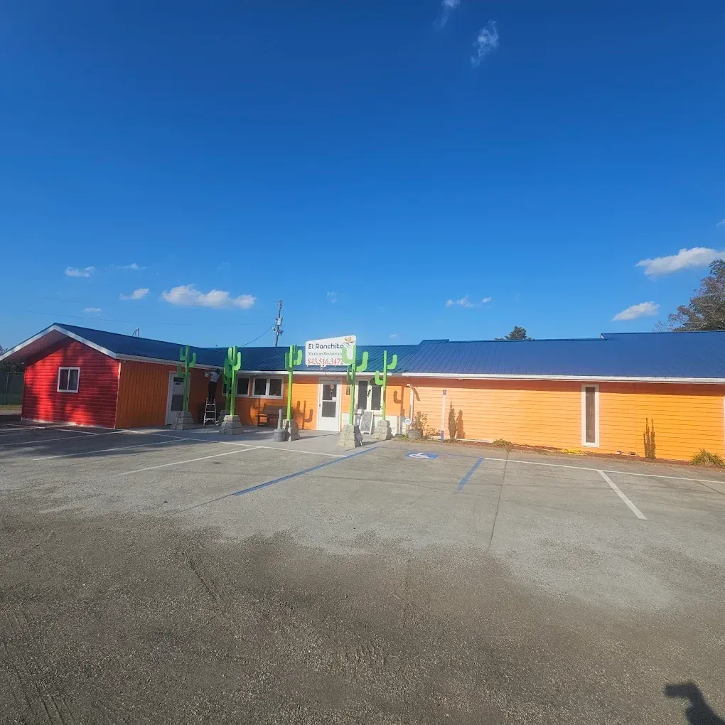 Brightly painted restaurant building with orange, red, and blue exterior. Cactus decor accents. Parking lot in front.