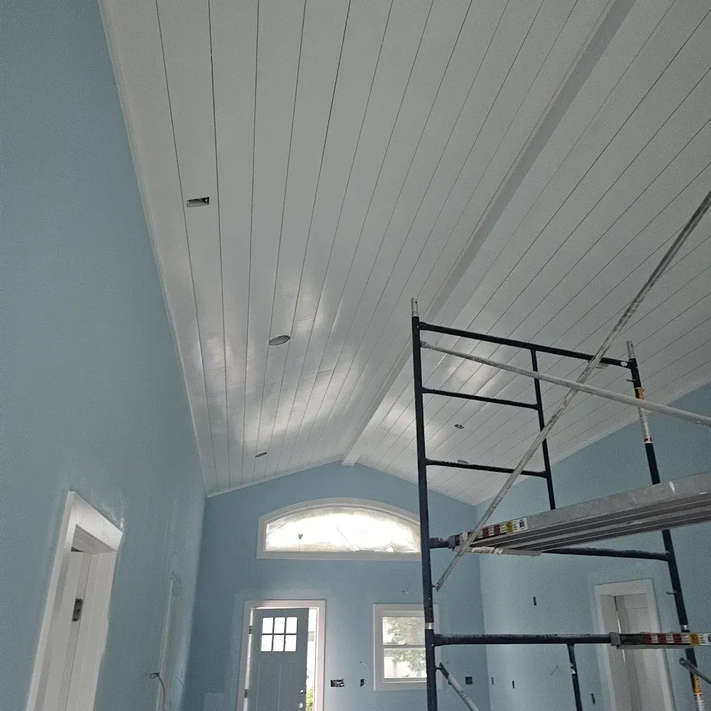 Interior of a room with a white plank ceiling, blue walls, and a metal scaffolding.