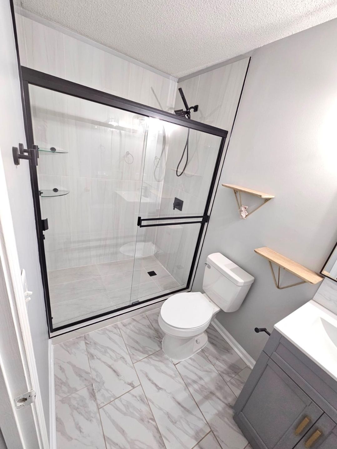 Narrow hallway with dark wood floors, white walls, and closed doors. A window is at the end of the hall.