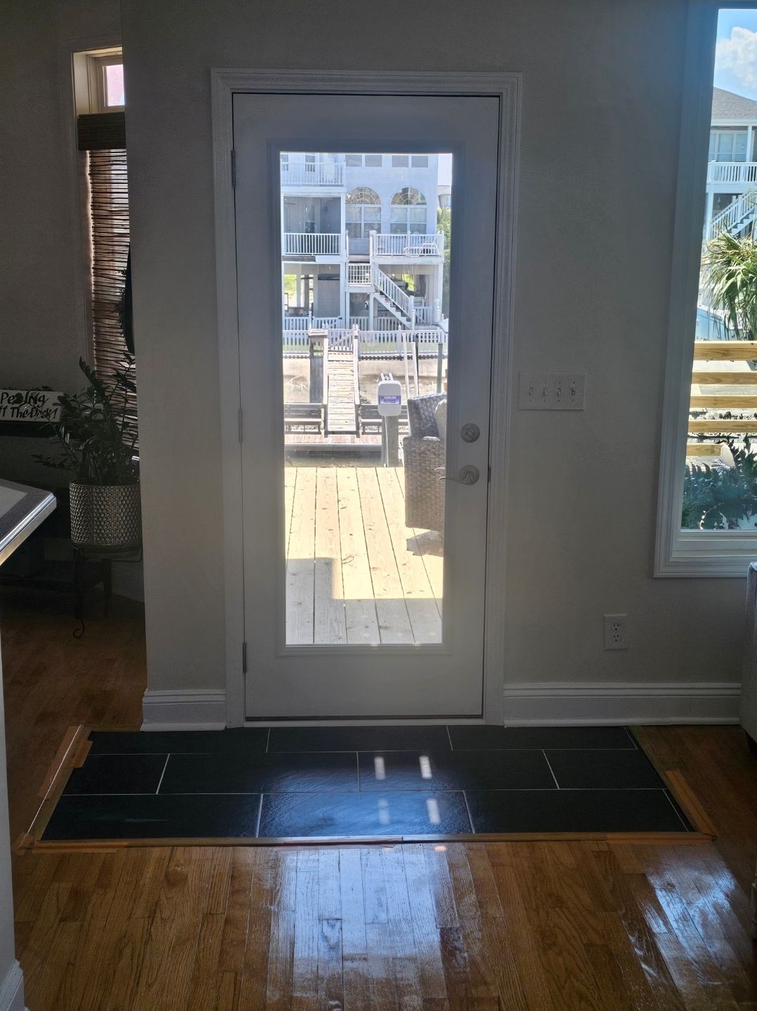 Narrow hallway with dark wood floors, white walls, and closed doors. A window is at the end of the hall.