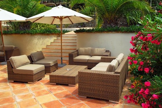 zona relax di un giardino con poltrone divani e ombrellone.
