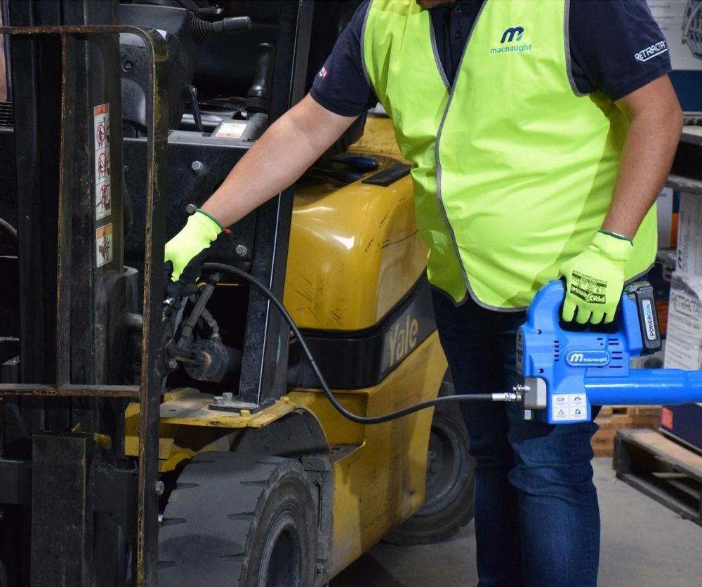 A Man in A Yellow Vest Is Working on A Forklift — Wades Distributors In Cairns, QLD