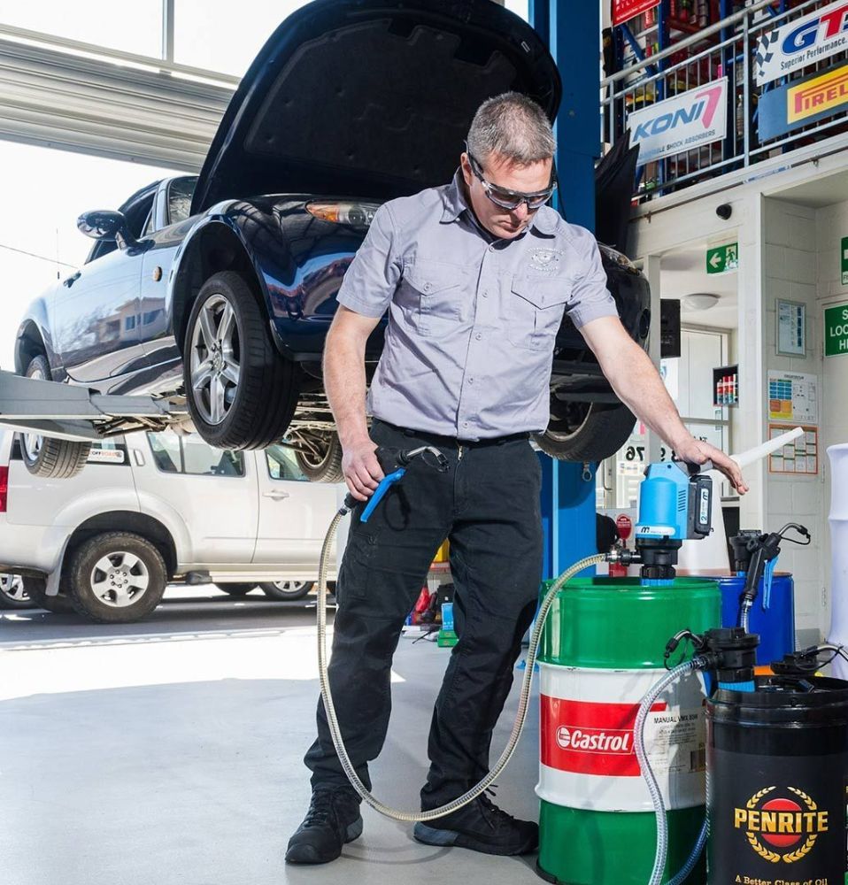 A Man Is Standing Next to A Green Barrel that Says Penrite on It — Wades Distributors In Whitsundays, QLD
