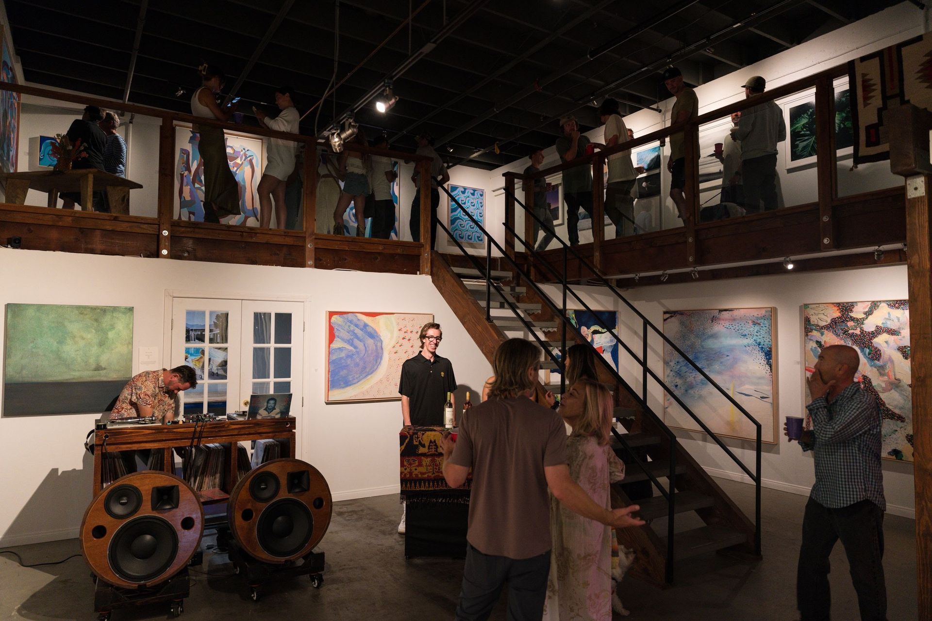 a group of people are standing in a Palm Palm Art Advisory room with speakers and stairs .