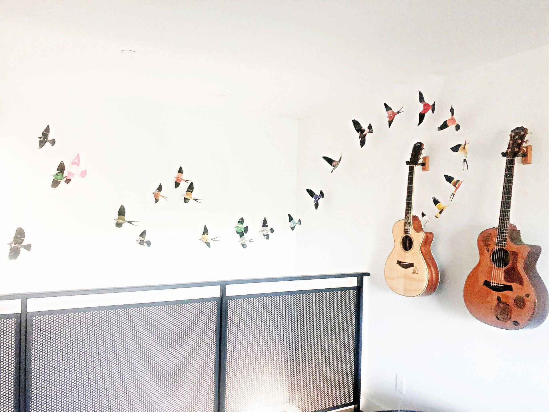 two guitars are hanging on a wall artfully placed.