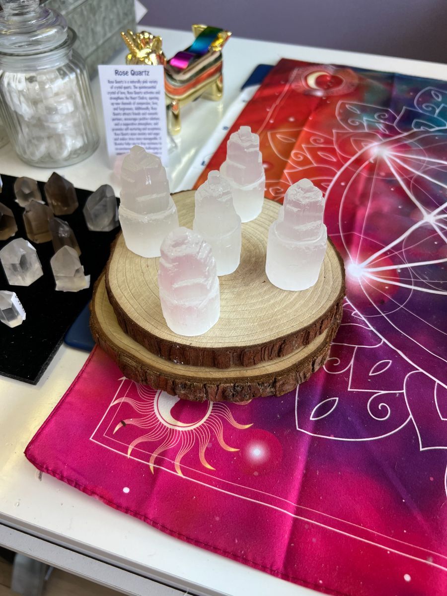Crystals displayed on a wooden stand with a colorful celestial-themed cloth in a shop setting.