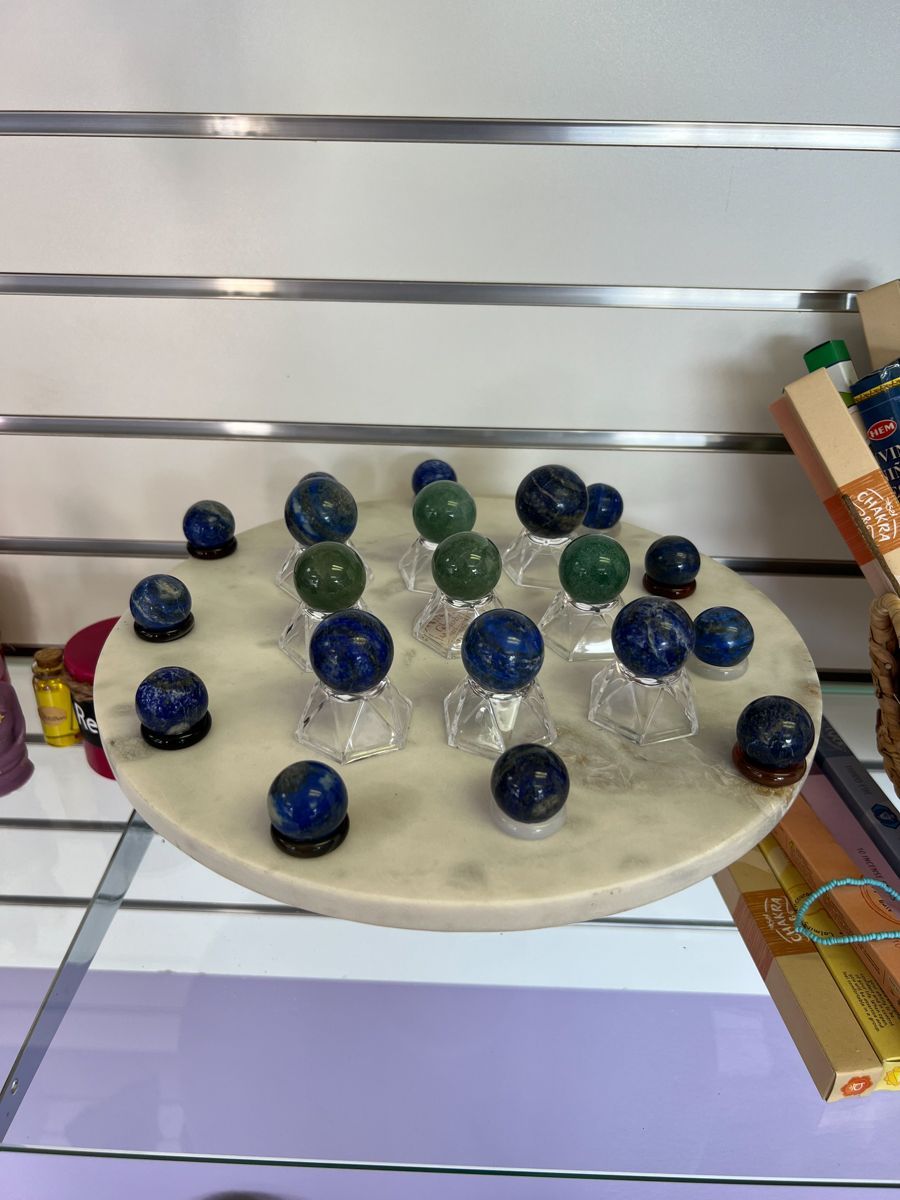 Display of various blue and green crystal balls on a white, circular platform.