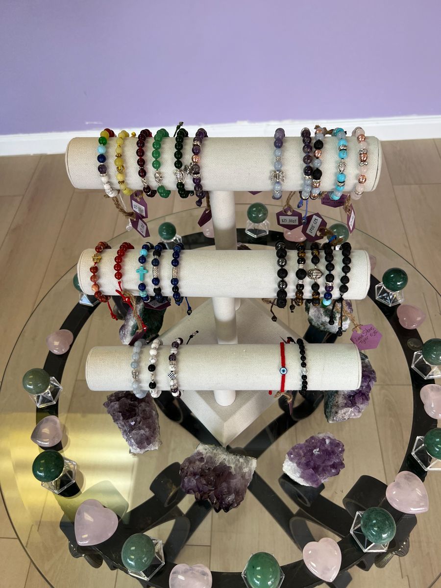 Jewelry display: bracelets on a tiered stand, surrounded by crystals and glass table.