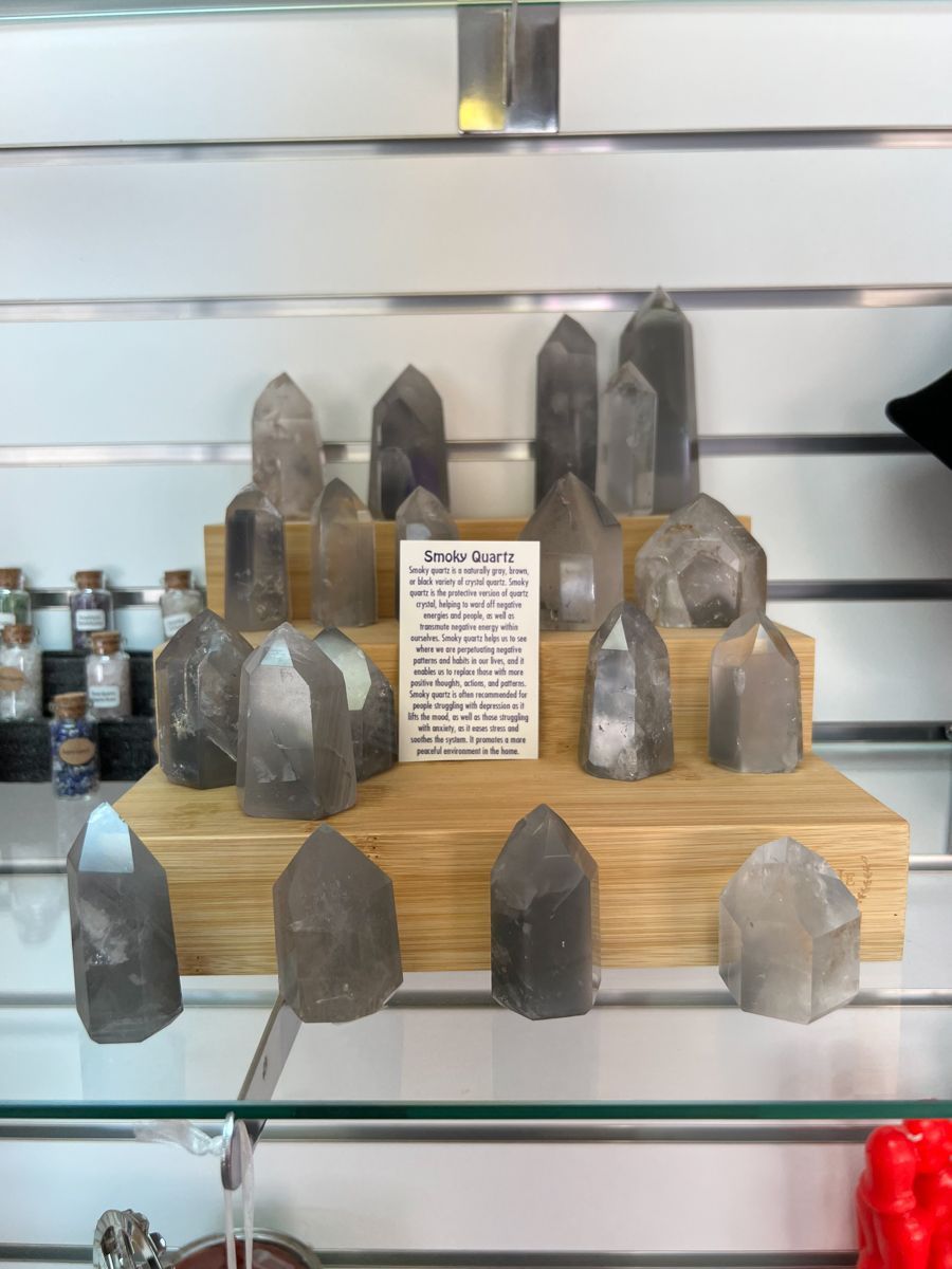 Display of smoky quartz crystals on a wooden shelf in a store, with a descriptive sign.