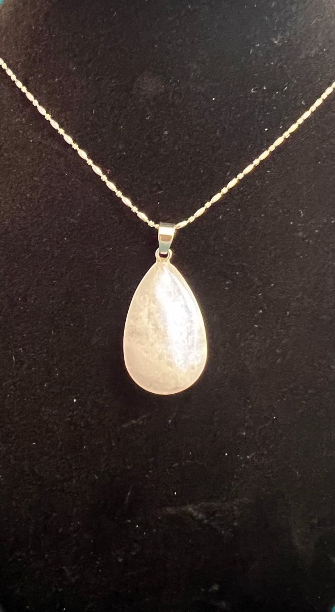Teardrop-shaped pendant necklace with a pearly, white stone on a silver chain.