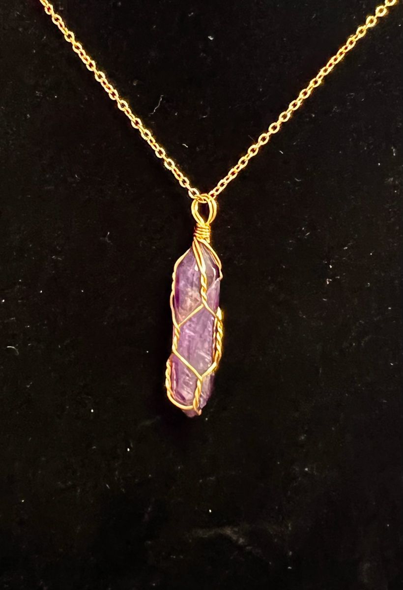 Gold chain necklace with purple crystal pendant, wire-wrapped in gold.