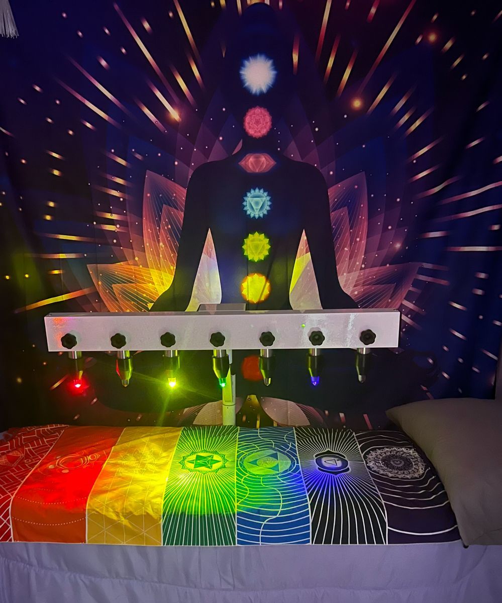 A therapy setup with colorful lighting, chakra chart, and bed.