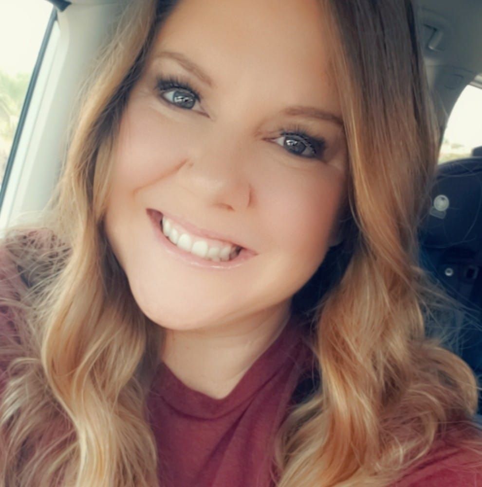 Travel advisor smiling, brown hair with highlights, wearing a maroon shirt, indoors, natural light.