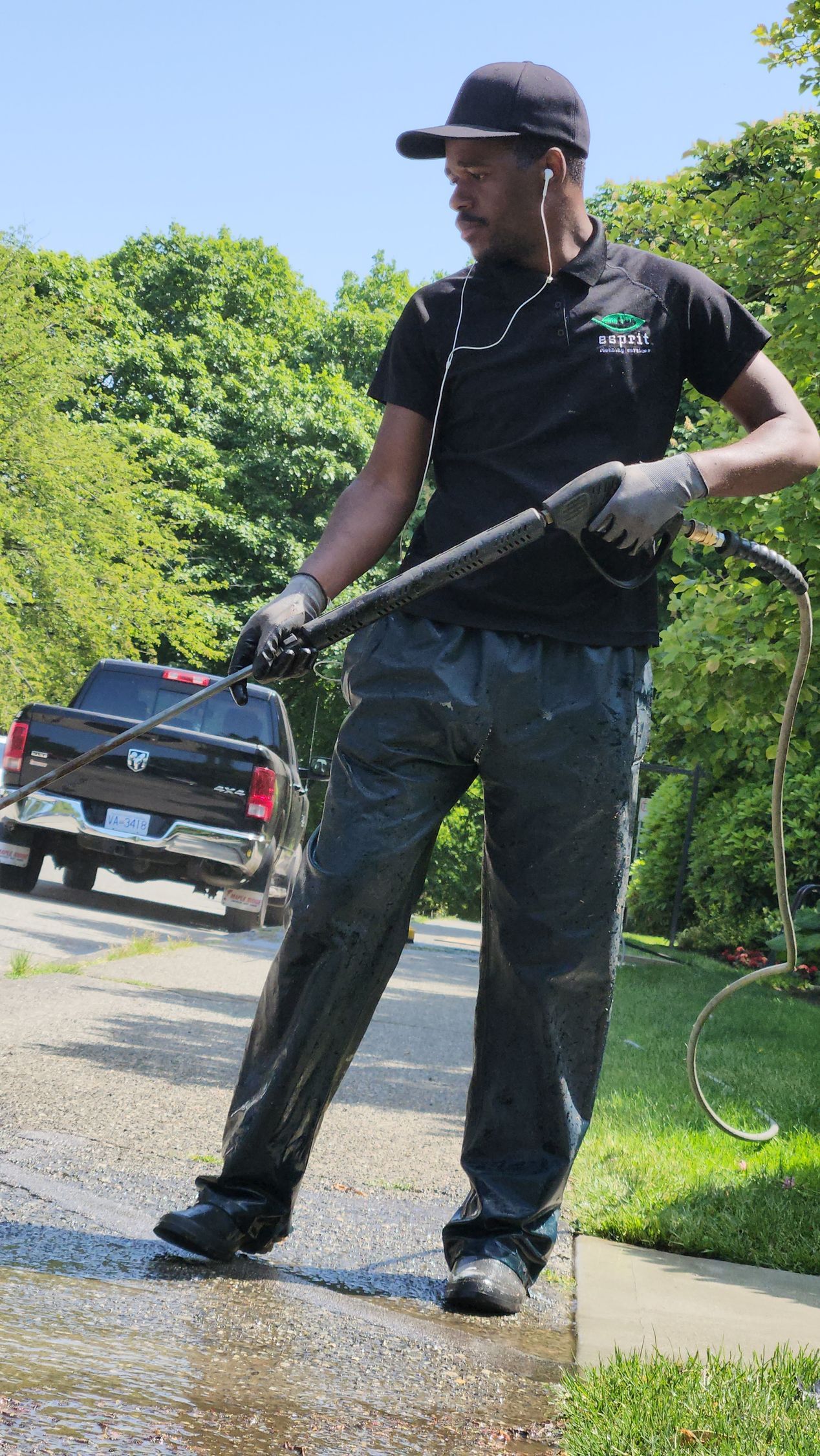 A man is standing on a sidewalk holding a high pressure washer.