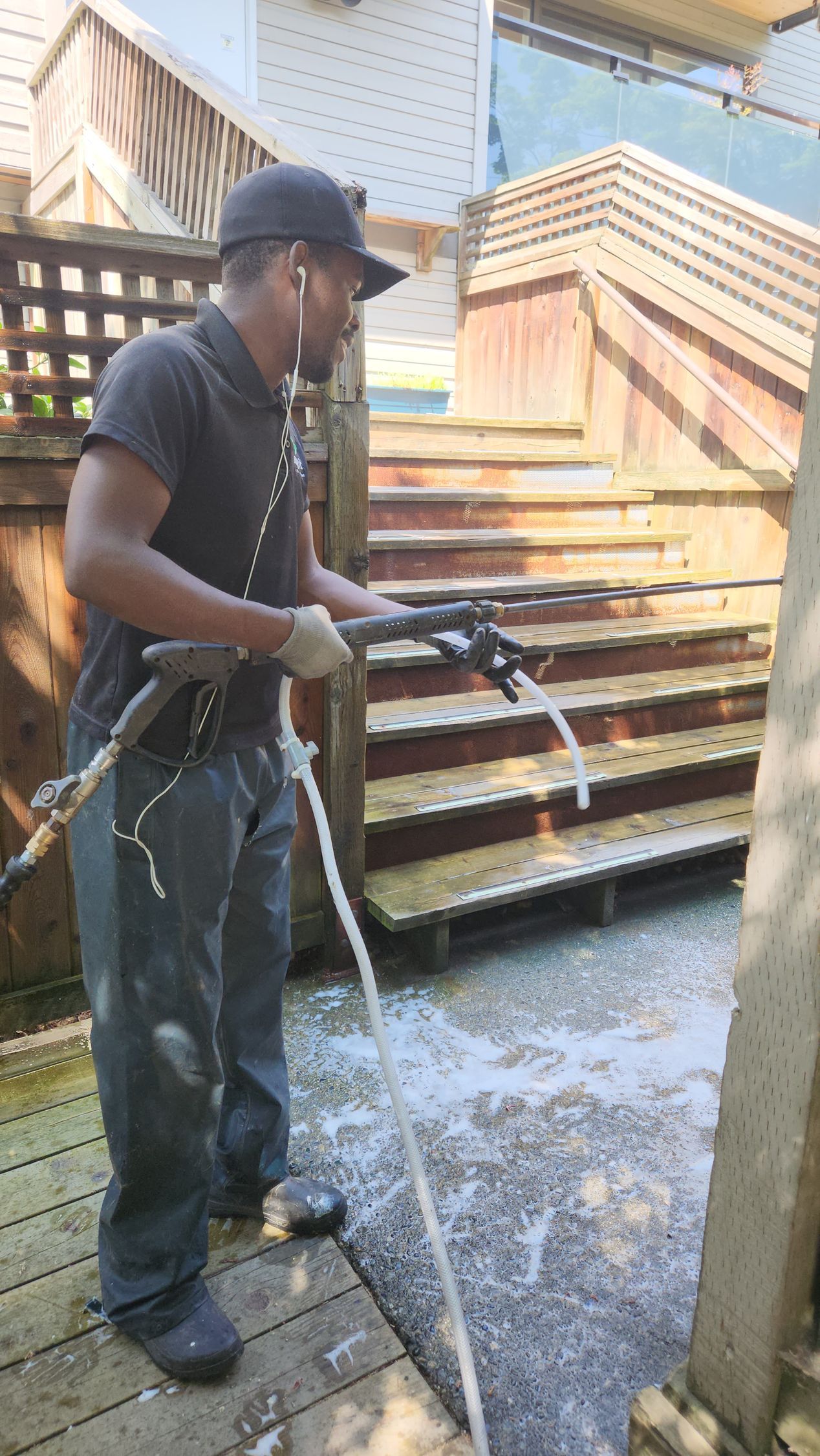 Man power washing wooden deck and stairs.