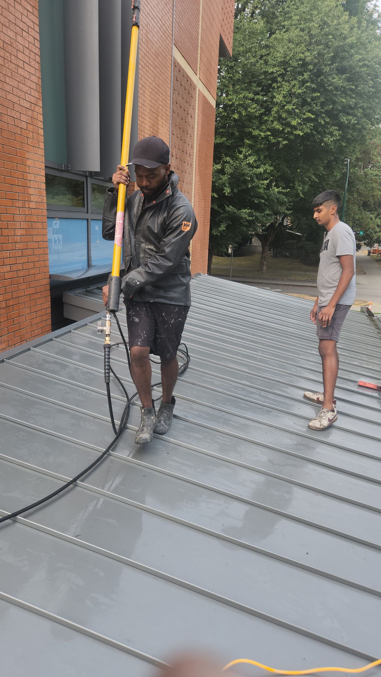 A man is standing on a roof holding a hose.