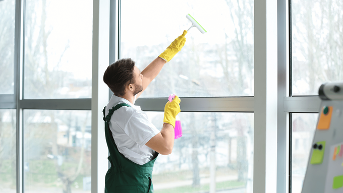 A man is cleaning a window with a squeegee.