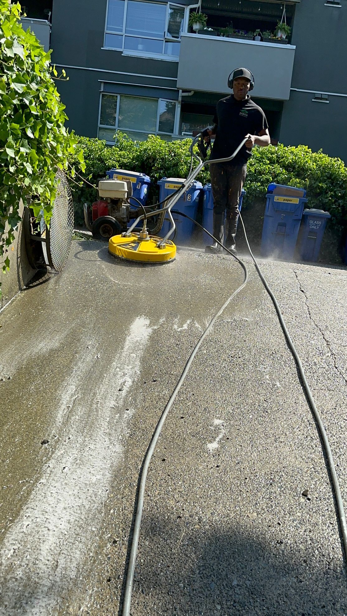 A man is using a machine to clean a concrete driveway.