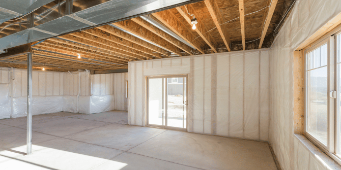 An empty basement with sliding glass doors and windows.