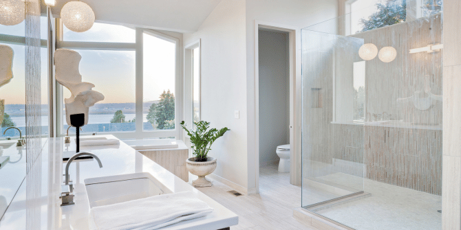 A bathroom with two sinks , a toilet , and a walk in shower.