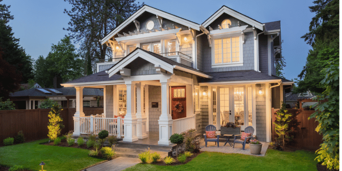 A large house with a large porch is lit up at night.