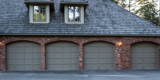 A large brick house with three garage doors and a slate roof.