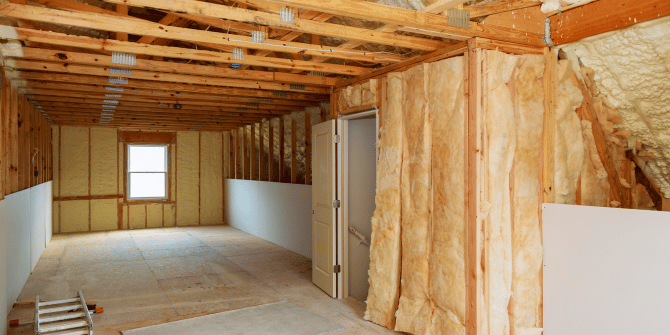 A room in a house under construction with wooden beams and insulation.