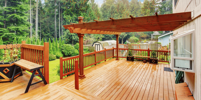 A wooden deck with a pergola and a bench.