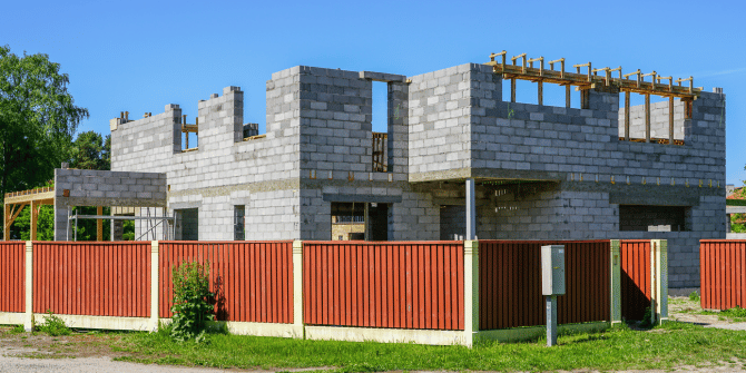 A house is being built with a red fence around it.