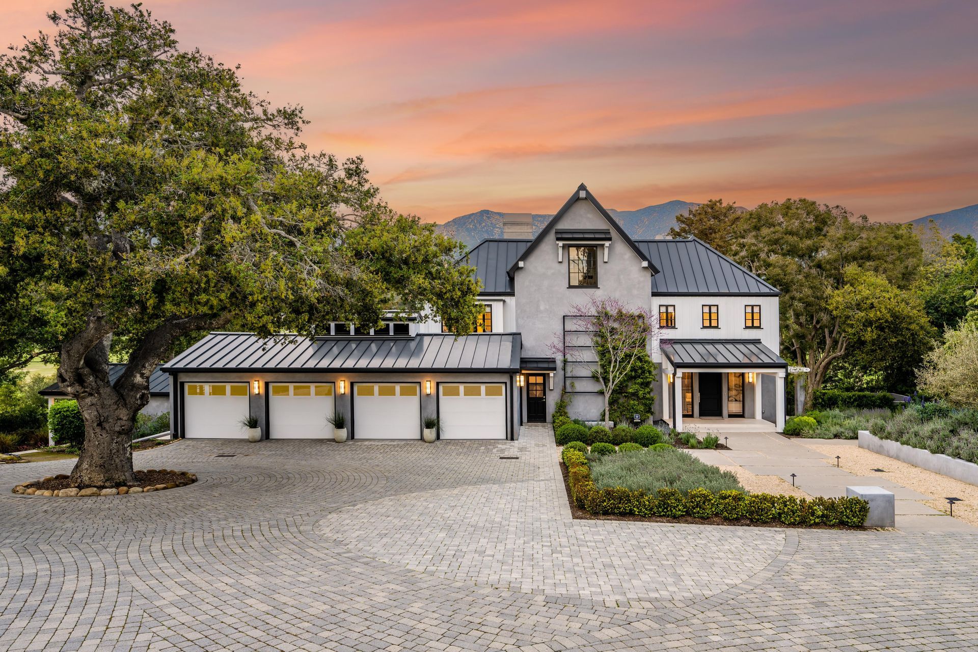 A large house with three garages and a tree in front of it