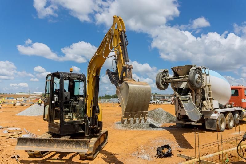 A bulldozer and a cement mixer are working on a construction site.