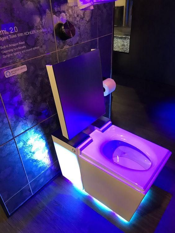 A toilet is lit up with purple lights in a bathroom.