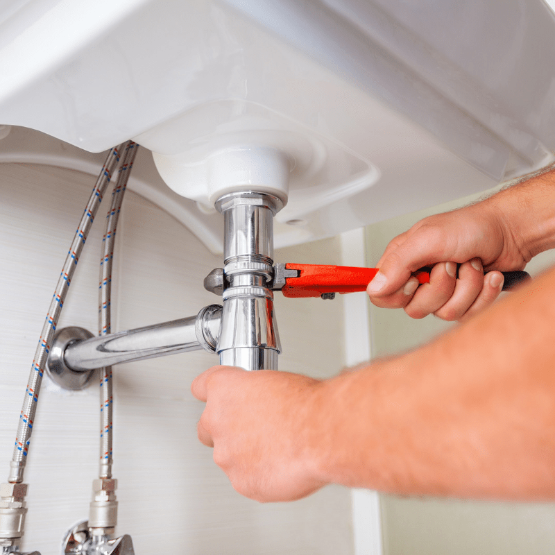 A man is fixing a sink with a wrench.