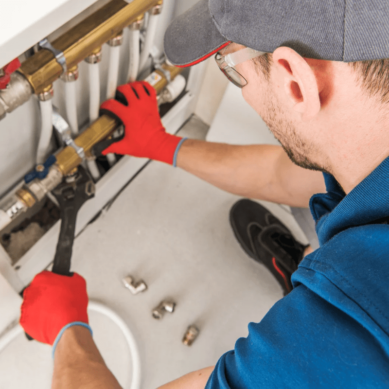 A man wearing red gloves is working on a pipe